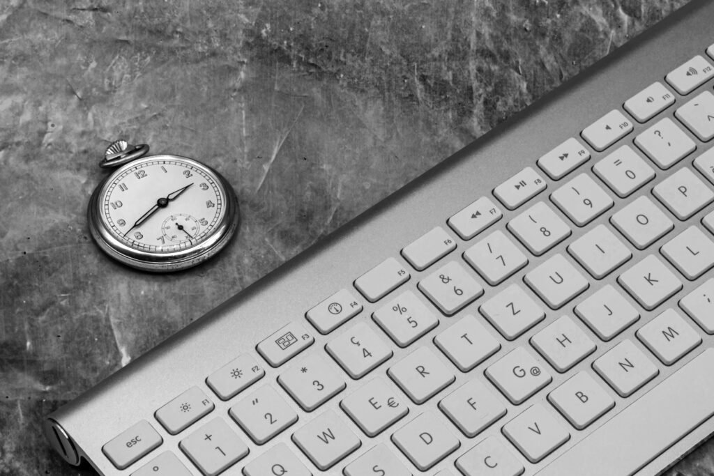 high-angle-view-computer-keyboard-with-pocket-watch-table